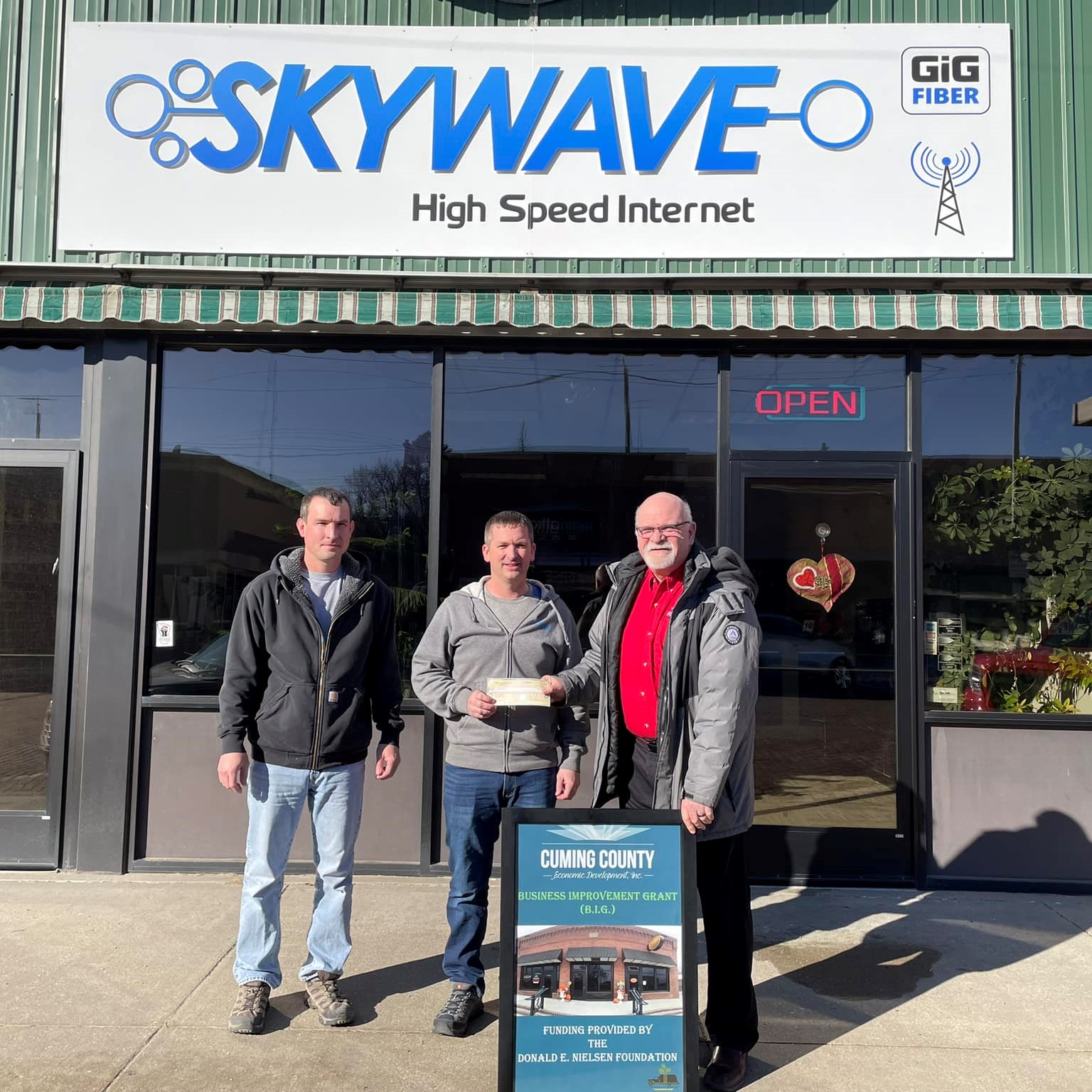 Skywave CEO, Craig Schmaderer & General Manager, Ryan Kuester - Accepting Grant Award for new store front sign from Cuming County Economic Development Director